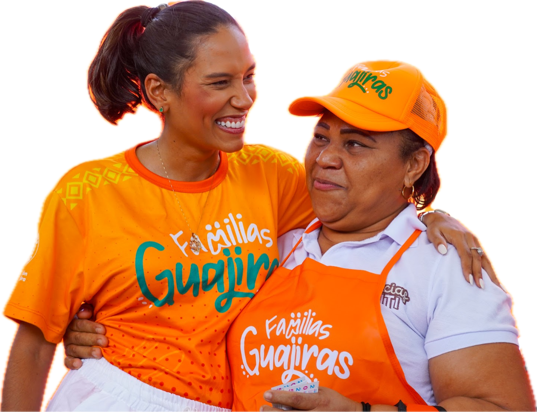 Dos mujeres de Familias Guajiras se abrazan sonriendo en la primera edición